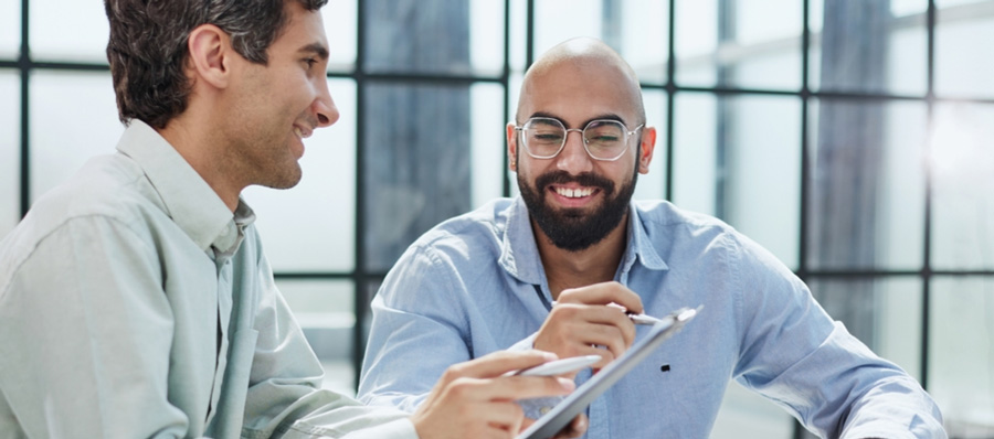 Two friends smiling while using embedded finance platform on laptop