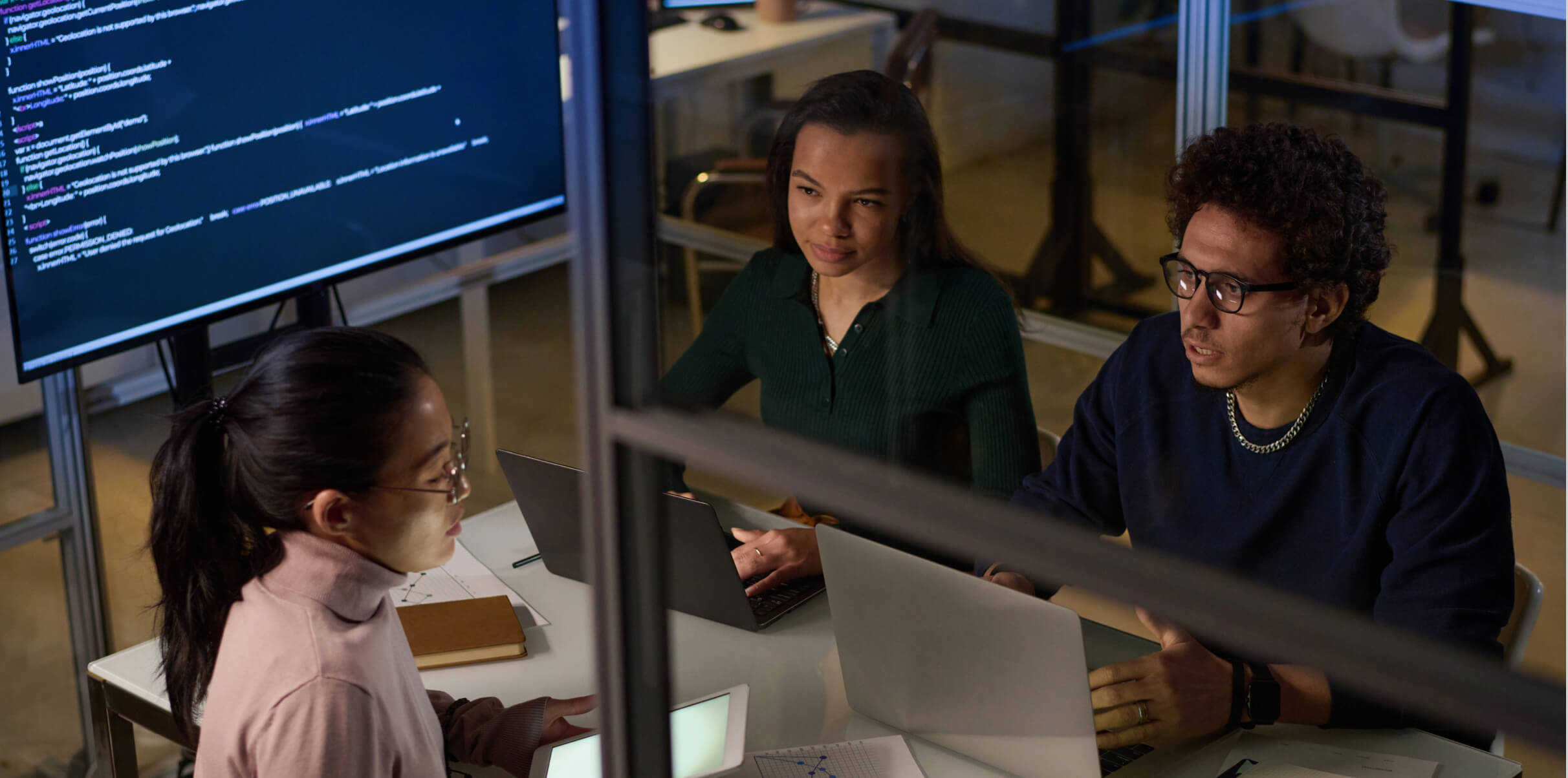 Group of developers on computers in a workspace, collaborating to create an AI-first architecture.