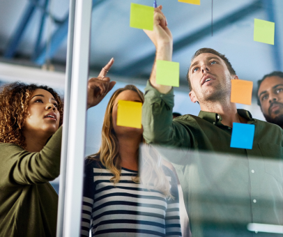 Team of young professionals brainstorming, pasting notes on wall