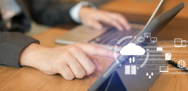 Person using laptop with cloud icon overlay, representing blockchain as a service (BaaS) model.